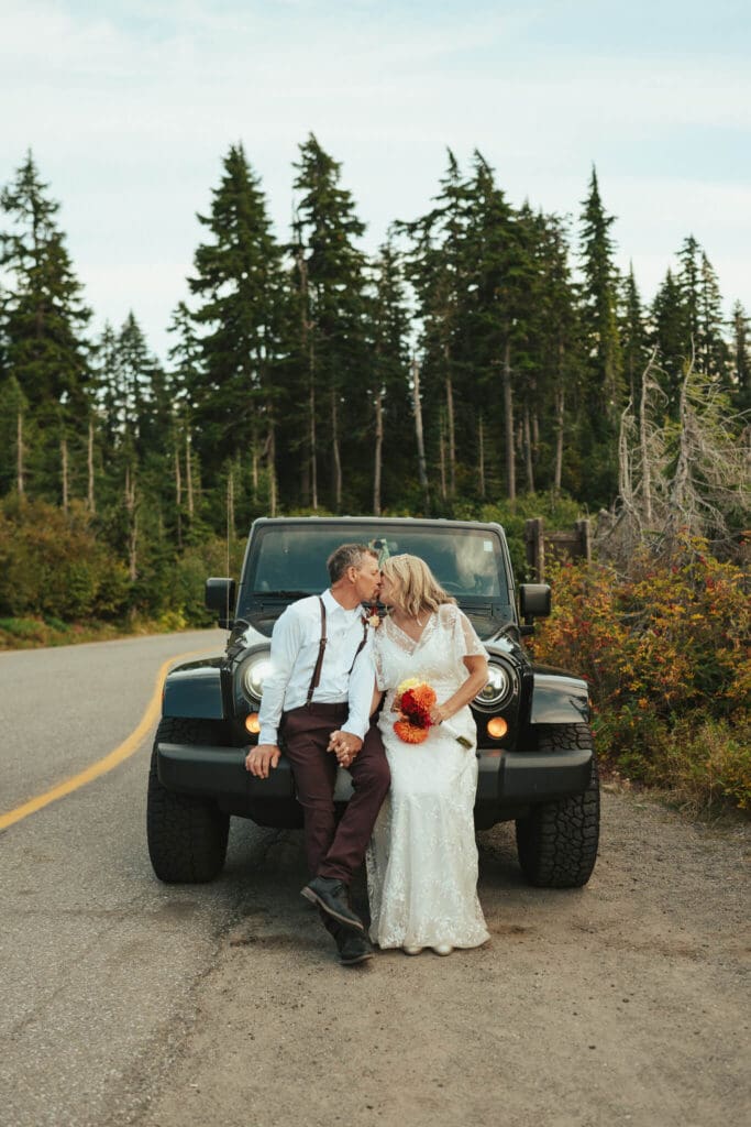 Couple sharing a quiet kiss after their Artist Point elopement while sitting on a Jeep along a mountain road.