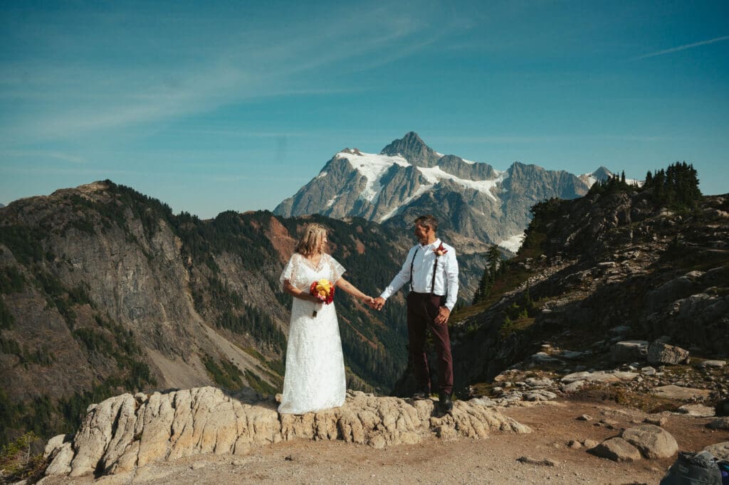 Couple holding hands during an Artist Point elopement with sweeping North Cascades mountain views.