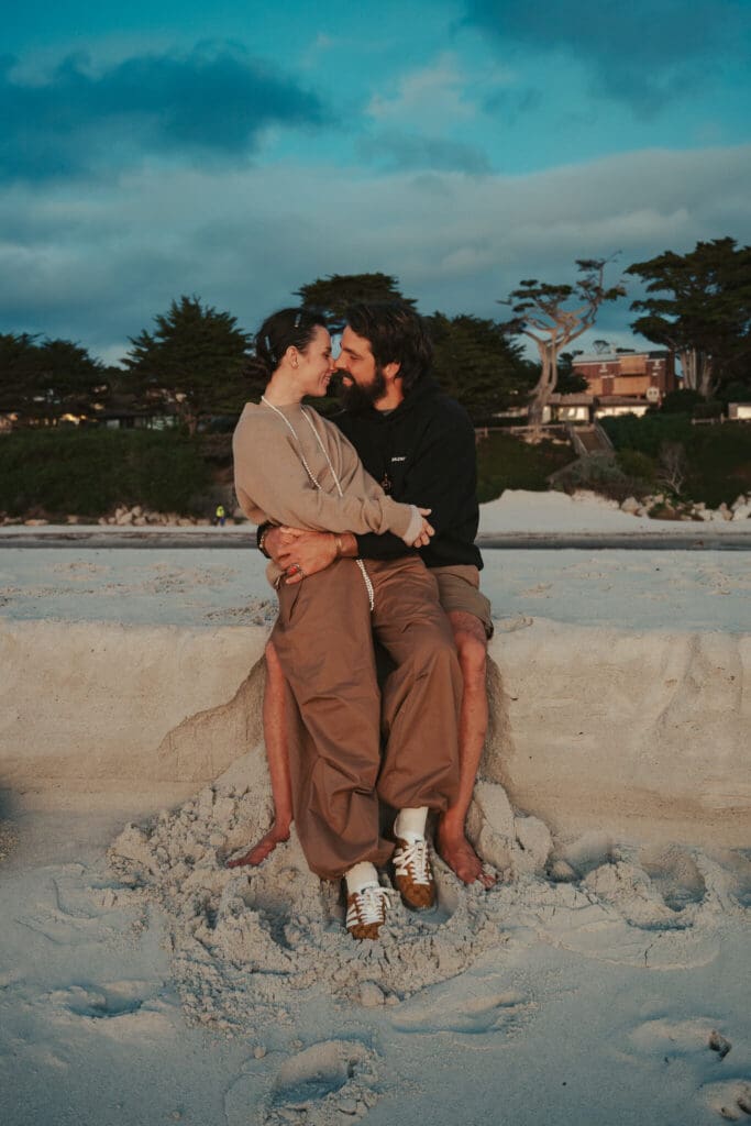 An intimate couples portrait on a Pacific Grove beach at sunset, surrounded by coastal light and Monterey Peninsula scenery.