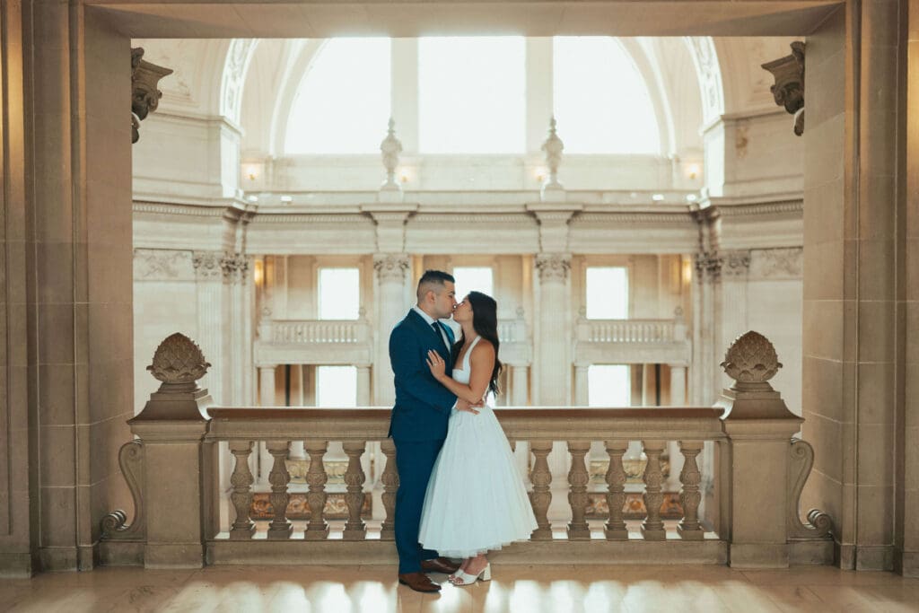 Couple sharing a romantic kiss on the balcony at San Francisco City Hall during an intimate elopement
