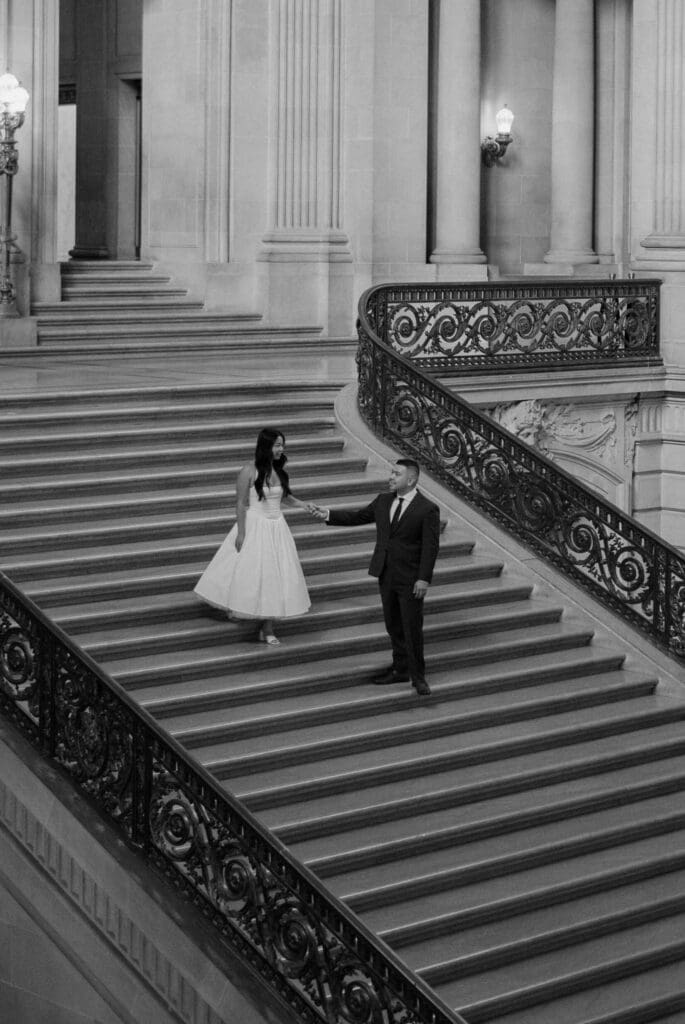 Black and white elopement photo of a couple on the grand staircase at San Francisco City Hall