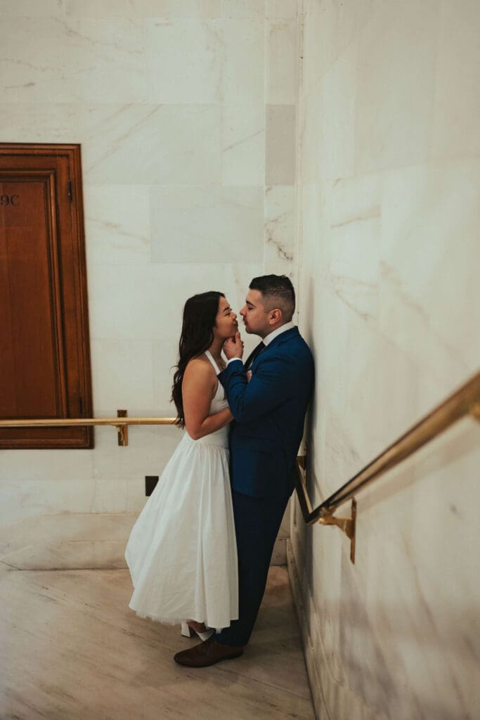 A moody, intimate kiss captured against the marble walls during a San Francisco City Hall elopement.