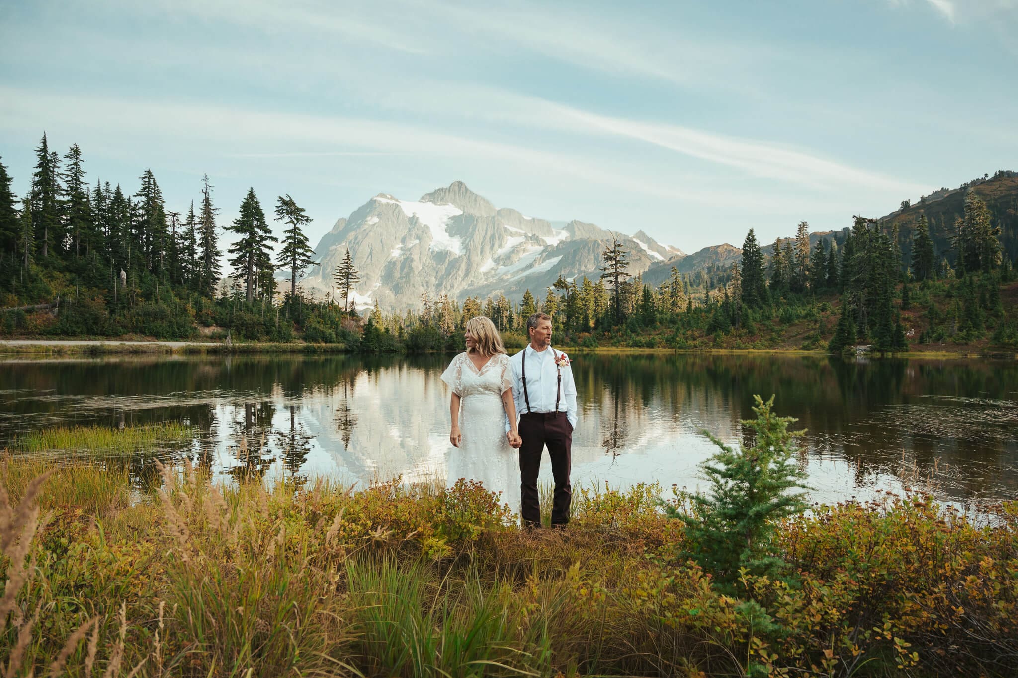 A wide lakeside wedding portrait at Picture Lake in Mt Baker National Forest surrounded by evergreen trees and mountain views, photographed by a Snohomish wedding photographer