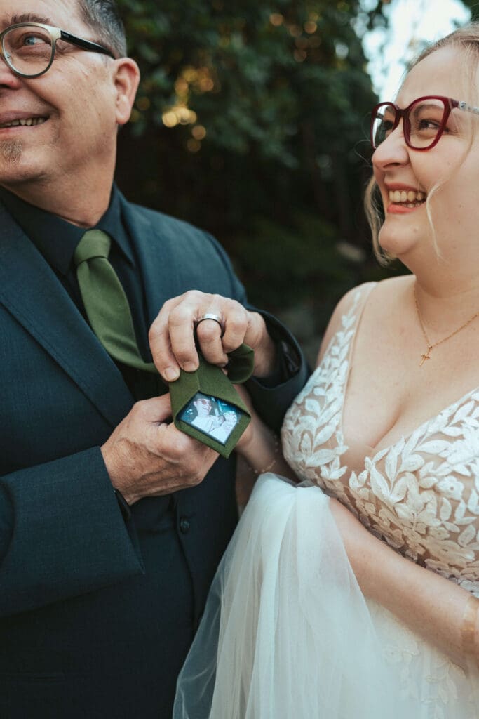 Father shows a hidden photo inside a tie during an emotional first look at a Floral Hall wedding in Everett, WA.