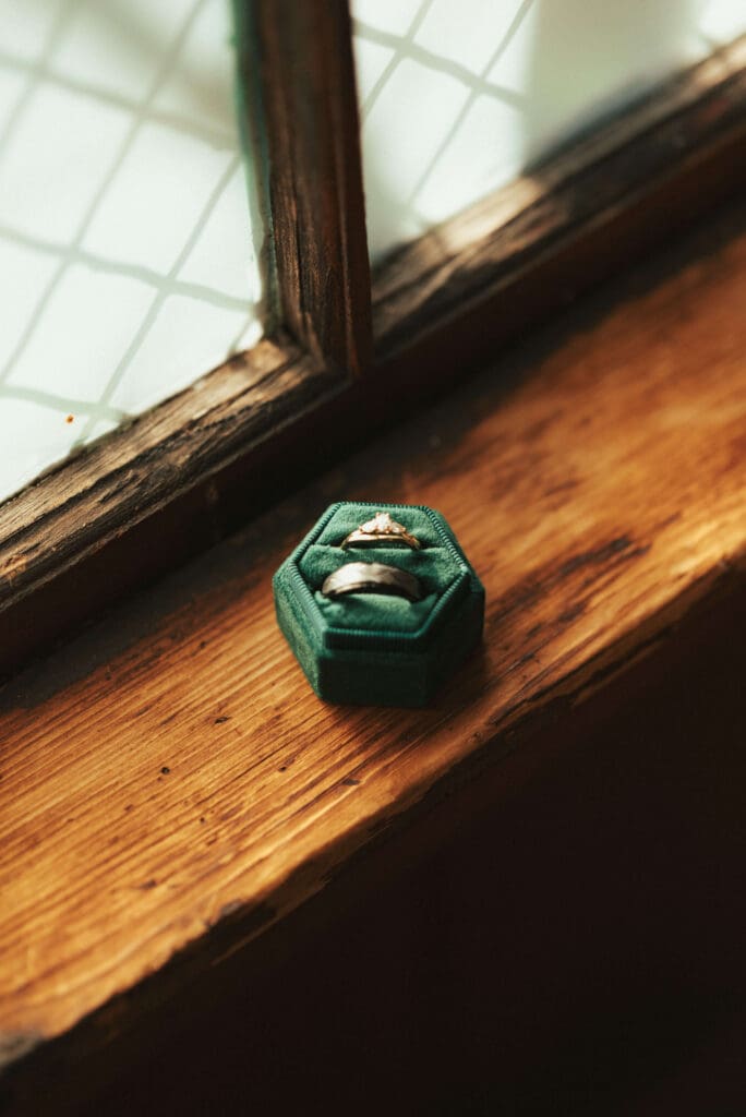 Wedding rings in a green velvet ring box in window light at Floral Hall in Everett, WA.