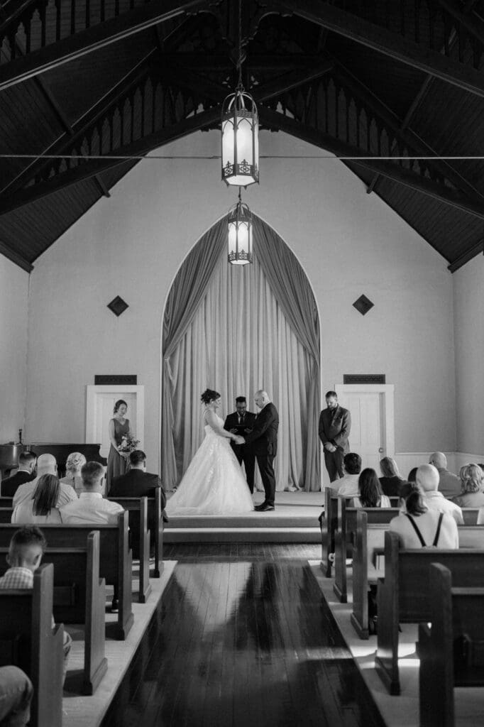 Wedding ceremony inside Belle Chapel in Snohomish, Washington, featuring cathedral ceiling and original hand-carved cedar trusses