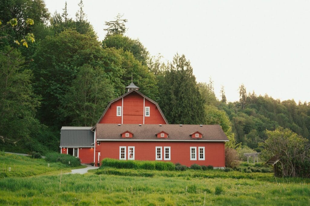 Historic red barn at Marionfield Farm wedding venue in Arlington, Washington, surrounded by lush green trees