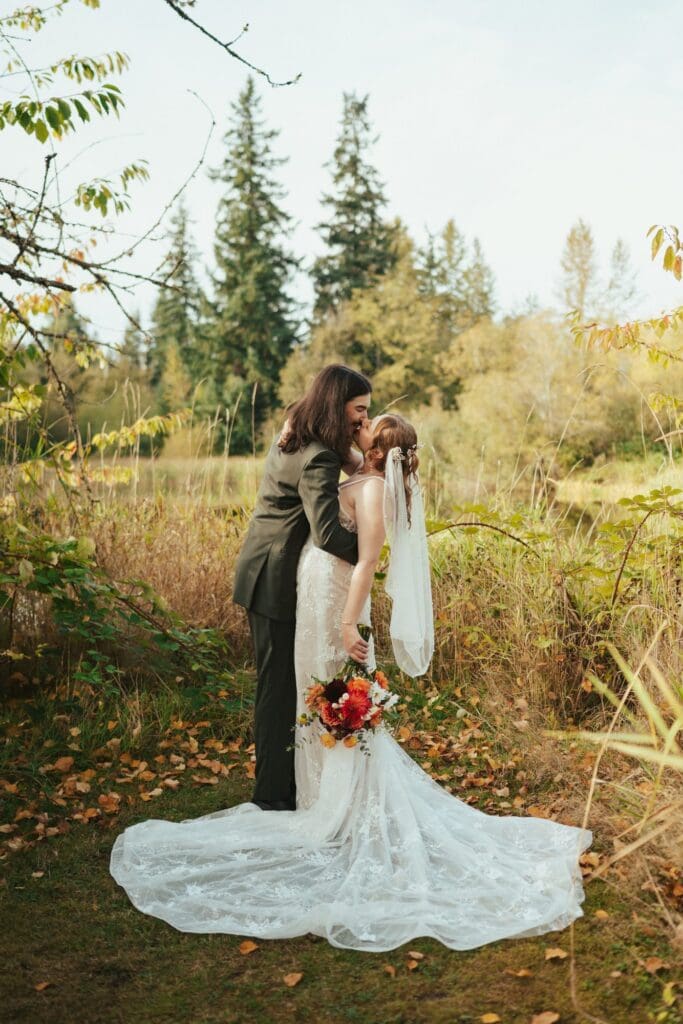 Bride and groom sharing a kiss in autumn foliage at Sadie Lake Events wedding venue in Arlington, Washington
