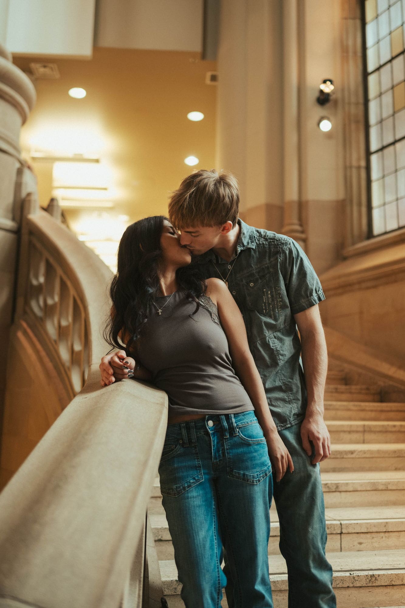 Couple kissing against a stone bannister on the stairs at Suzzallo Library in Seattle